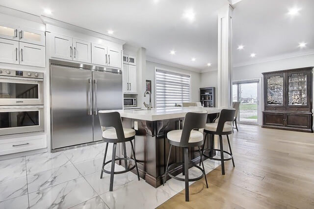 Spacious white kitchen with chocolate island and quartz countertops.